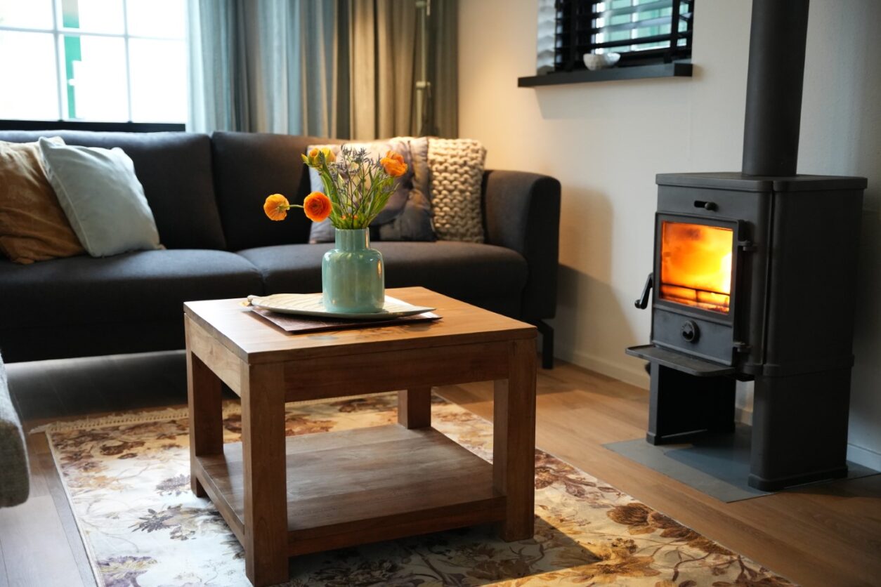 Blick ins gemütliche Wohnzimmer des Ferienhaus Appelbloesem mit Sofa, Holztisch und brennendem Kamin