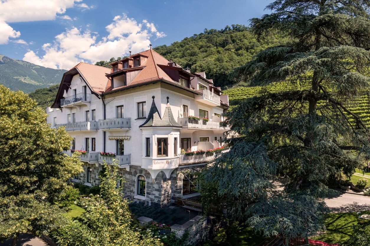 Außenaufnahme des Ladurnerhof, einem Jugendstilgebäude inmitten von Bäumen und Weinreben