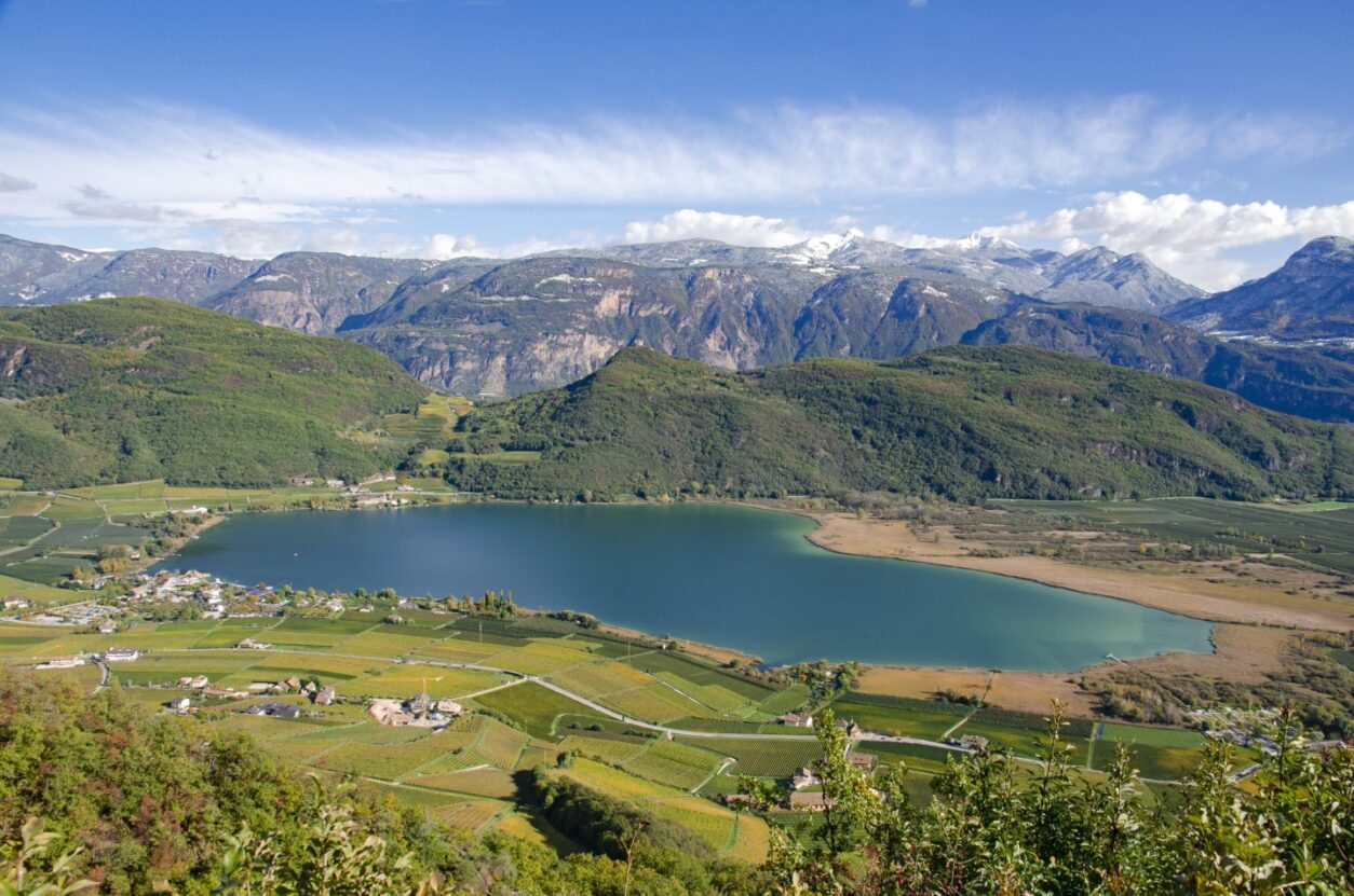 Blick vom Berg auf Kalterer See, die Weingüter drumherum sowie die Berge im Hintergrund