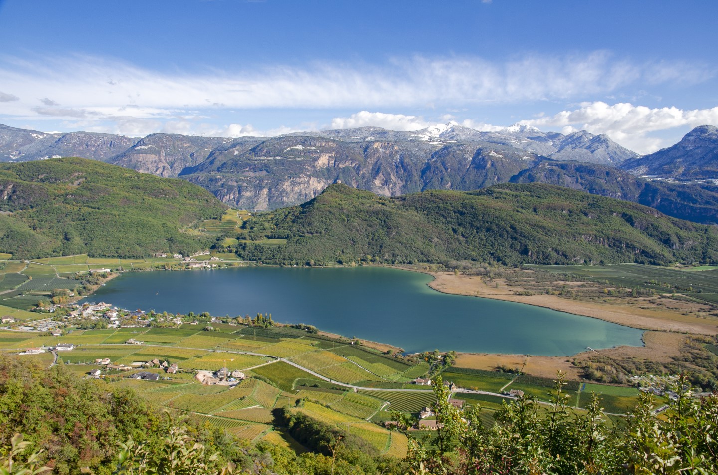 Blick vom Berg auf Kalterer See, die Weingüter drumherum sowie die Berge im Hintergrund