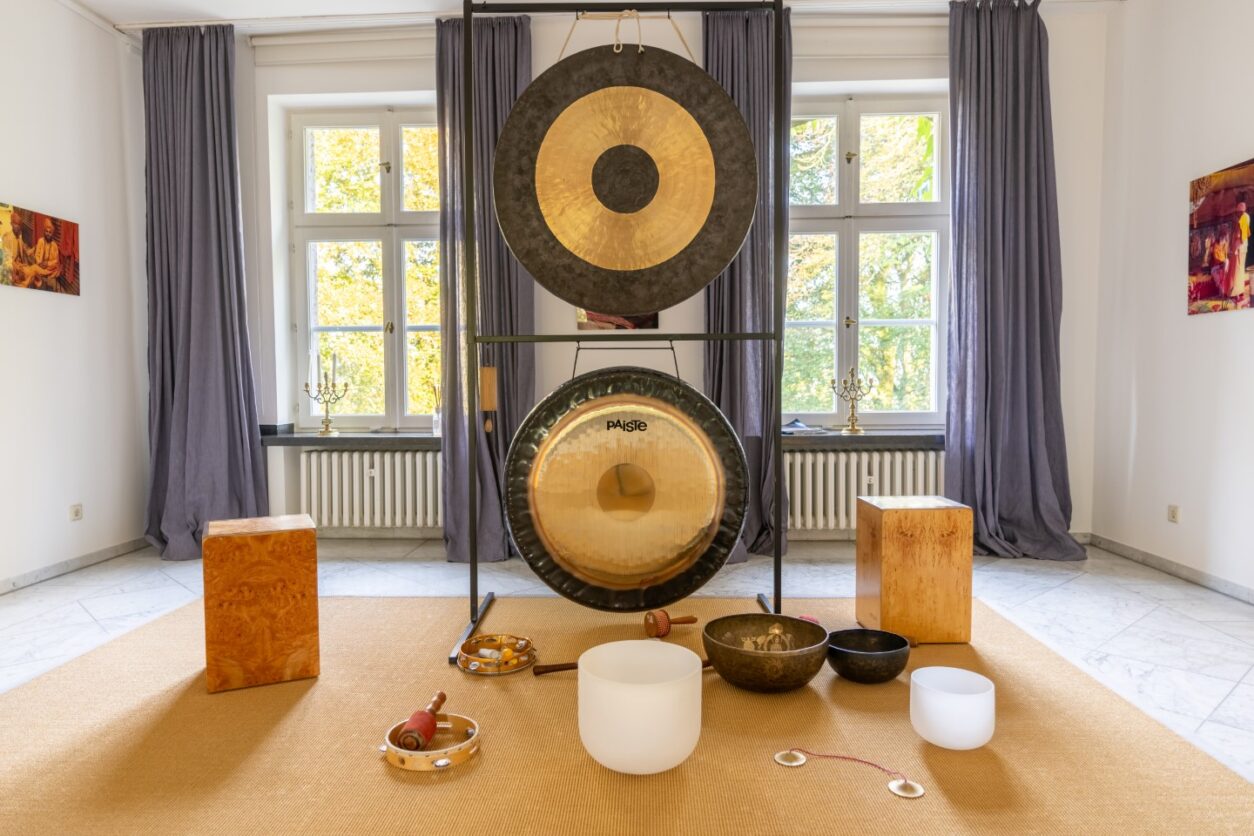 Große, senkrecht stehende Gongs sowie Klangschalen zur Musiktherapie stehen auf einem Teppich