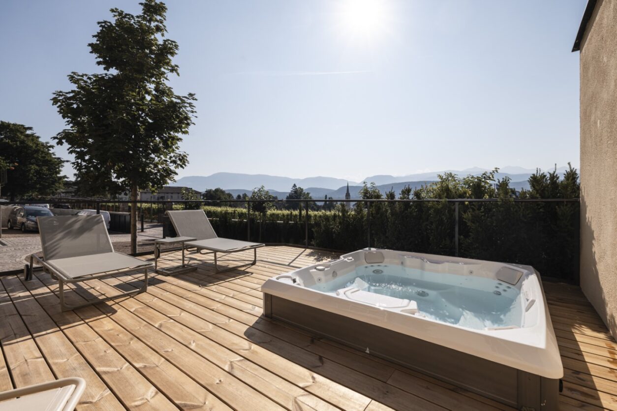 Die gemeinsame Außenterrasse der Ferienwohnungen Kaltern mit Holzdielen, Whirlpool und traumhafter Aussicht