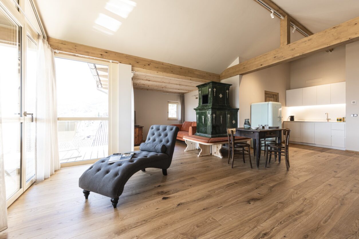 Der große Wohnbereich mit Kachelofen, Küchenzeile und Essbereich einer der Ferienwohnungen Kaltern, Essa Suites