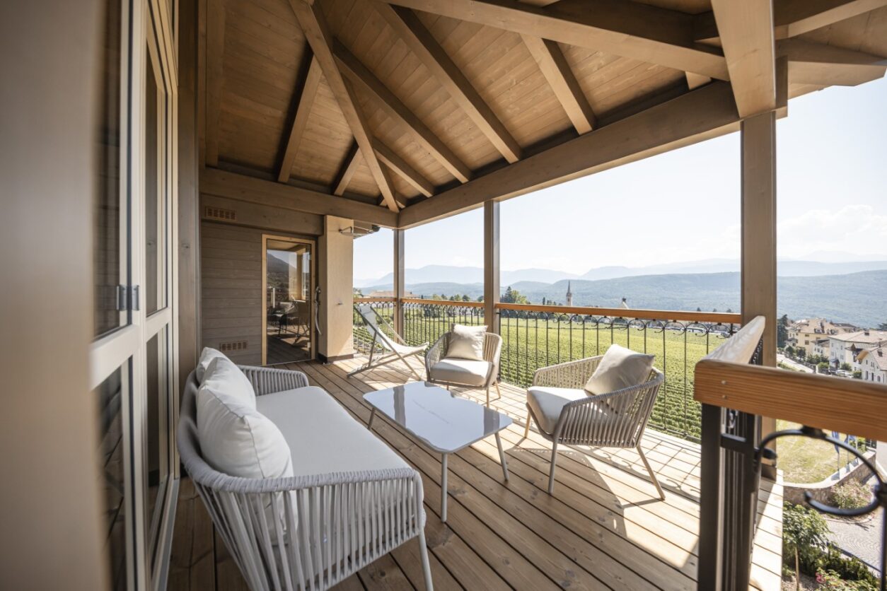 Großer überdachter Holzbalkon mit Sitzmöbeln und Panoramablick in einer der Ferienwohnungen Kaltern