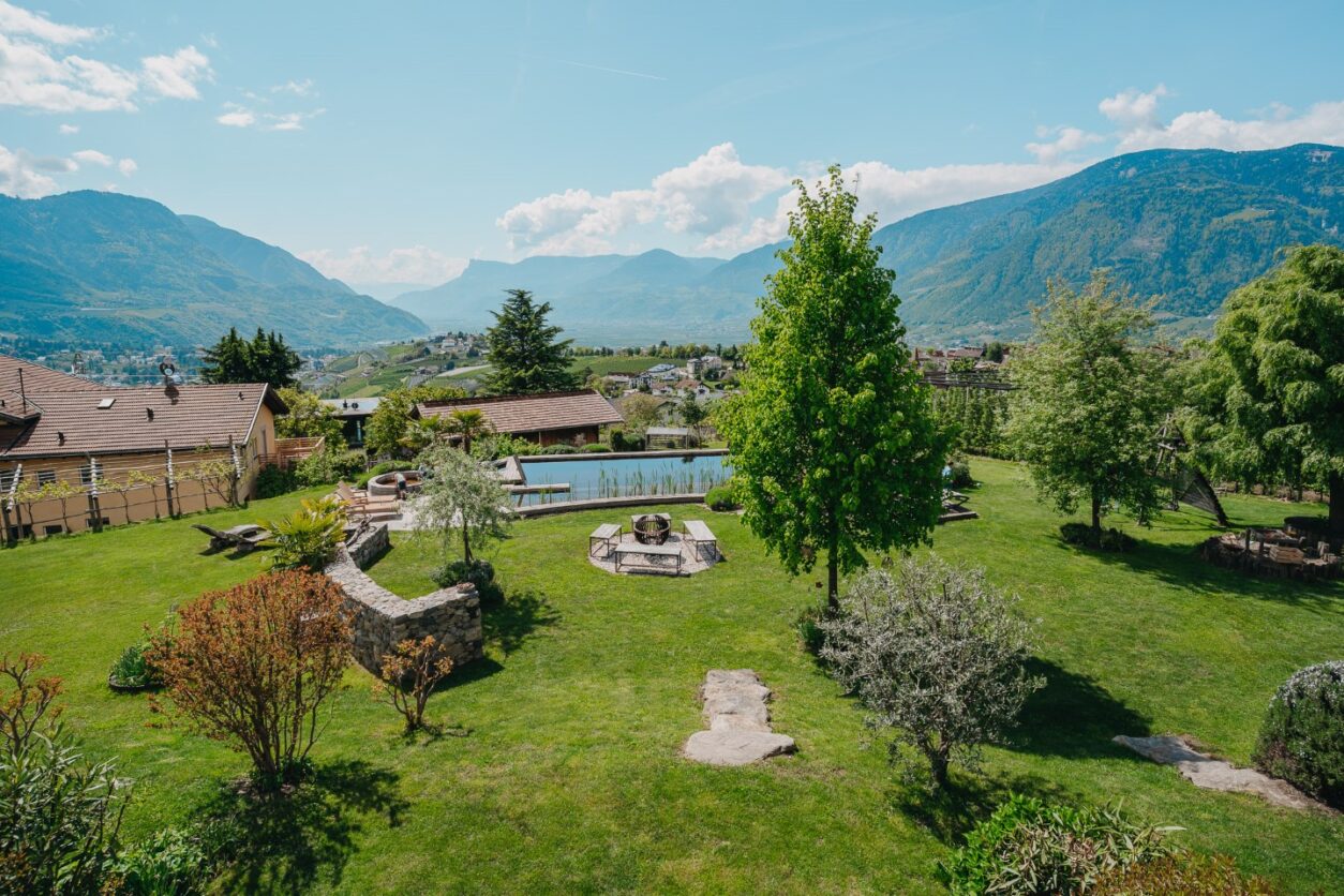 Blick vom Gebäude mit den Ferienwohnungen Meran über den großen Garten und den Pool bis ins Tal bei Meran