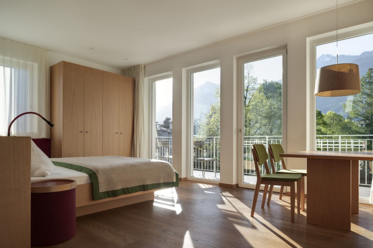 Das schöne Schlafzimmer einer Ferienwohnung Meran im Ladurnerhof mit Doppelbett und großen, bodentiefen Fenstern