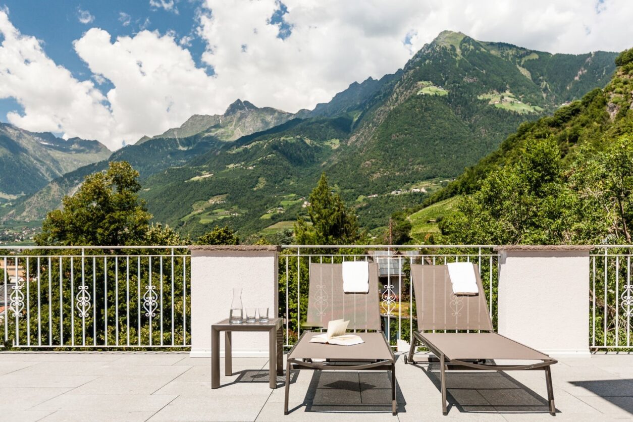 Terrasse einer Ferienwohnung mit zwei Sonnenliegen und Panoramablick auf die Berge