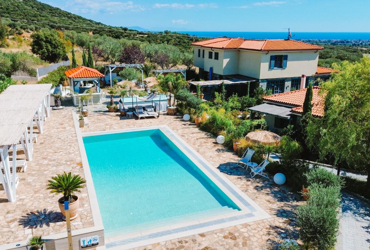 Außenpool des Ioniso Boutique Hotels mit Hotelgebäuden, Garten und Blick auf das Meer